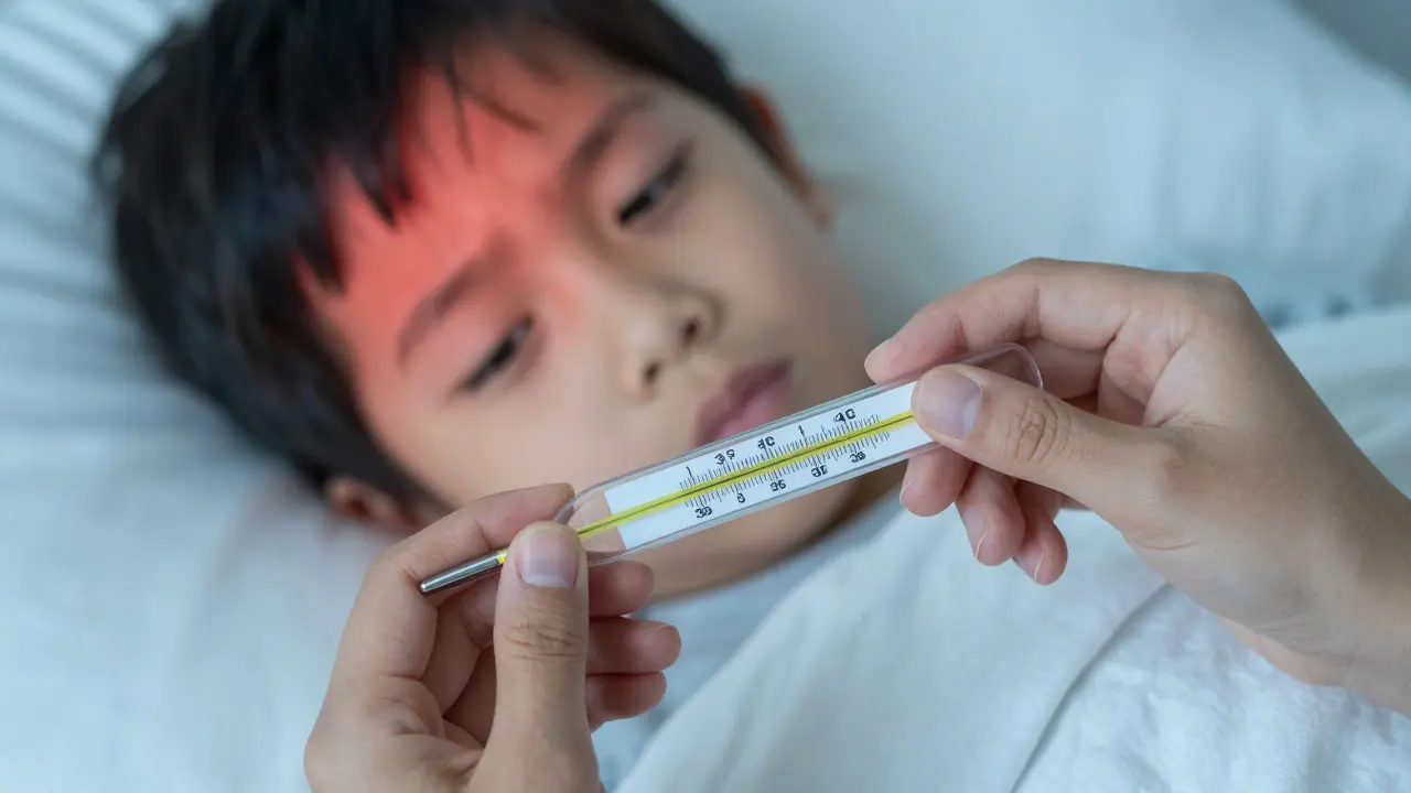 Záběr na teploměr ukazující vysokou teplotu a třesoucího se dítěte